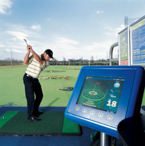 A golfer hitting a ball at Top Golf with the launch monitor in the foreground. 